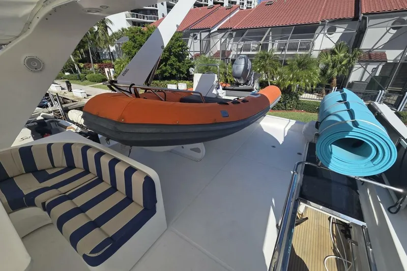 Slide: The Image of 2009 Grand Harbour 66 Motoryacht deck with striped seating, orange dinghy, and blue mat. - 8