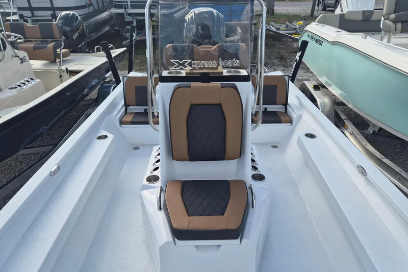 Slide: The Image of 2026 Xpress H24B Bay boat interior with tan and black seating, showcasing console and cup holders. - 10
