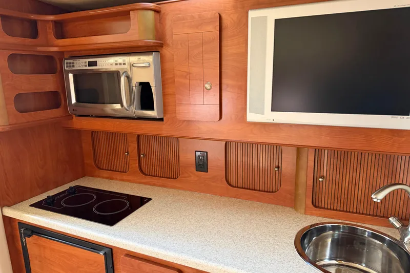 Slide: The Image of 2007 Rinker EX 370 boat interior kitchen with microwave, stove, sink, and TV. - 20