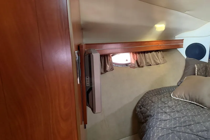 Slide: The Image of 2007 Rinker EX 370 cabin interior with bed, TV, and porthole window. - 24