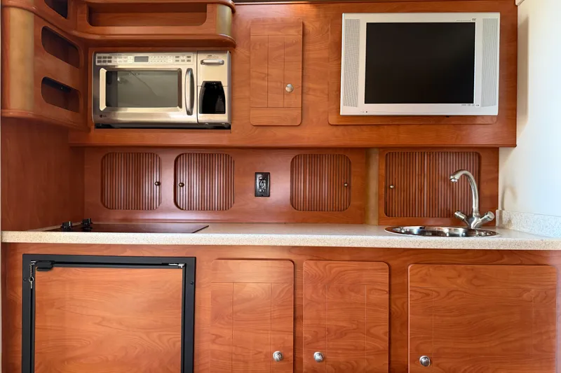 Slide: The Image of 2007 Rinker EX 370 yacht interior with microwave, TV, sink, and wooden cabinetry. - 27