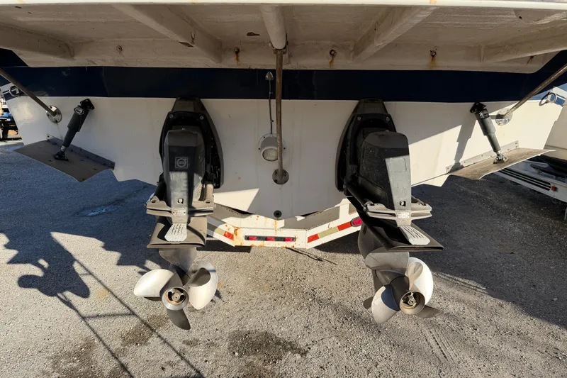 Slide: The Image of 2007 Rinker EX 370 boat stern with dual propellers and outdrives in a parking area. - 34