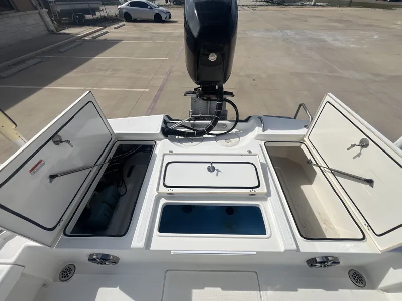 Slide: The Image of 2014 Mako 21 LTS boat with open storage compartments and motor. - 23