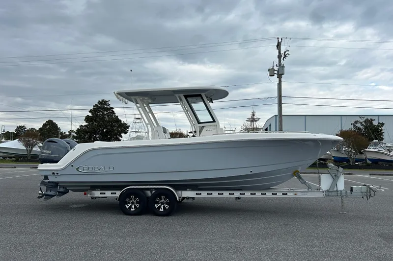 The Image of 2021 Robalo R272 Center Console boat on trailer, parked outdoors under cloudy sky. - 0