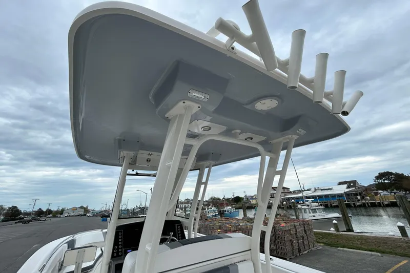 Slide: The Image of 2021 Robalo R272 Center Console boat with T-top and rod holders at a marina. - 14