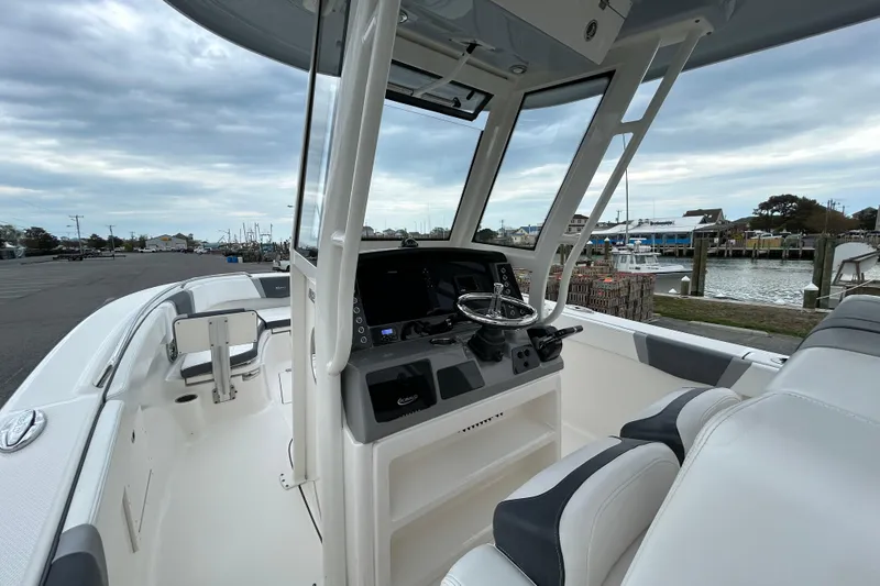 Slide: The Image of 2021 Robalo R272 Center Console boat interior with steering wheel and seating, dockside view. - 15