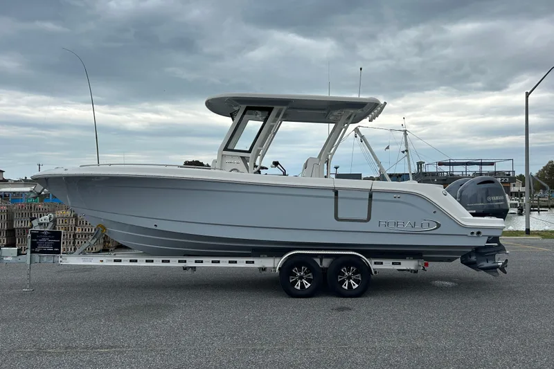 Slide: The Image of 2021 Robalo R272 Center Console boat on trailer, parked near marina under cloudy sky. - 4