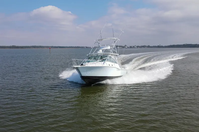 The Image of 1995 Cabo 35 Express boat cruising on open water under a partly cloudy sky. - 0