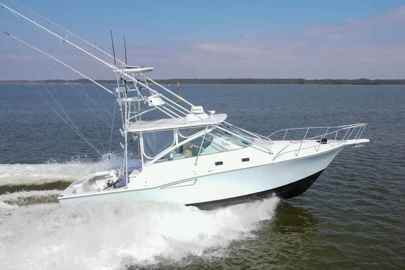 Slide: The Image of 1995 Cabo 35 Express boat cruising on open water, creating a wake. - 1