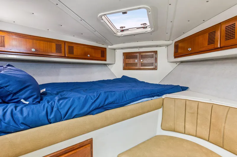 Slide: The Image of 1995 Cabo 35 Express cabin interior with blue bedding and wooden storage cabinets. - 36