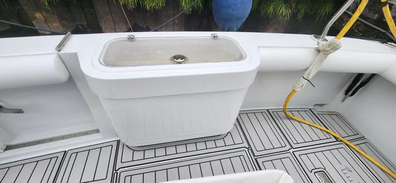 Slide: The Image of 1995 Cabo 35 Express boat deck with storage compartment and hose. - 51