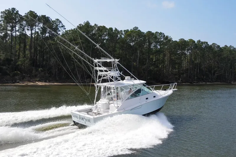 Slide: The Image of 1995 Cabo 35 Express boat cruising on a scenic river with forested shoreline. - 72