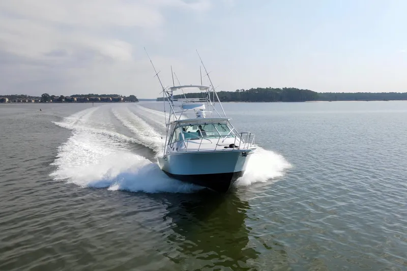 Slide: The Image of 1995 Cabo 35 Express boat cruising on a calm lake, leaving a wake behind. - 75