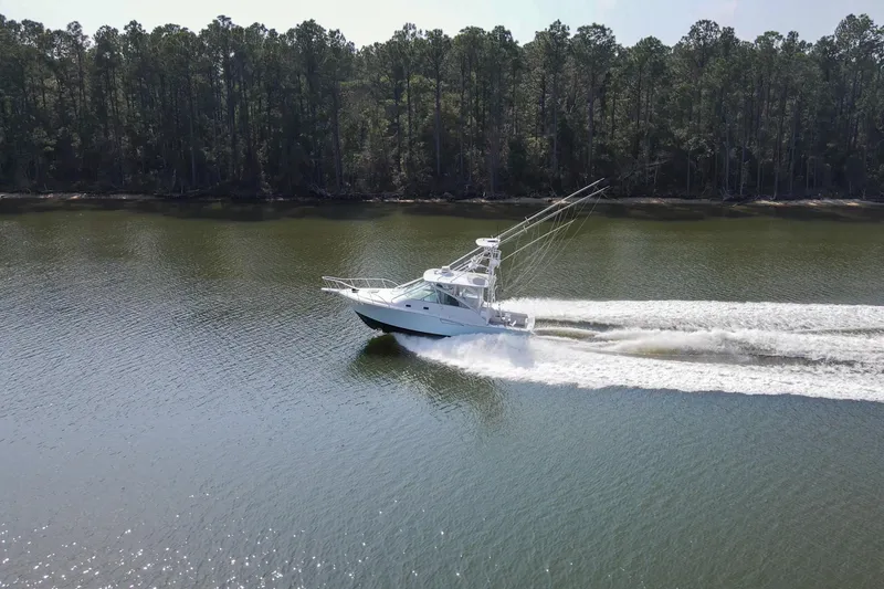 Slide: The Image of 1995 Cabo 35 Express boat cruising on a calm river with forested shoreline. - 76