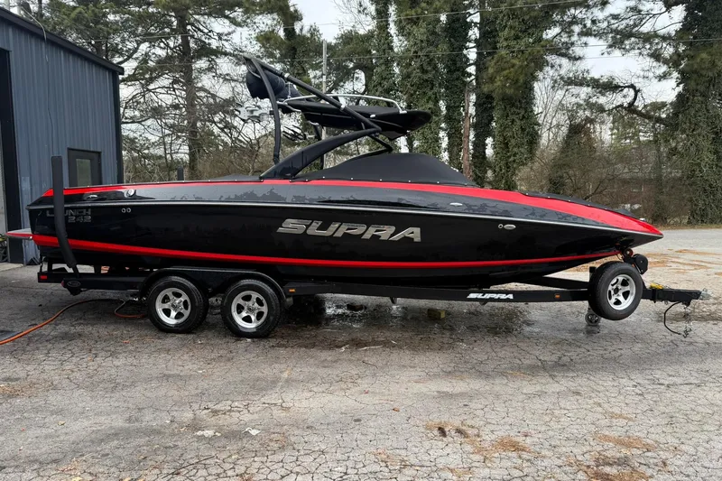 Slide: The Image of 2011 Supra Launch 242 boat on trailer, black and red design, parked outdoors. - 3