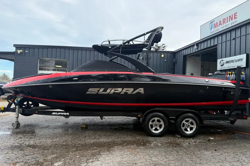 Slide: The Image of 2011 Supra Launch 242 boat on trailer outside marine service shop. - 7