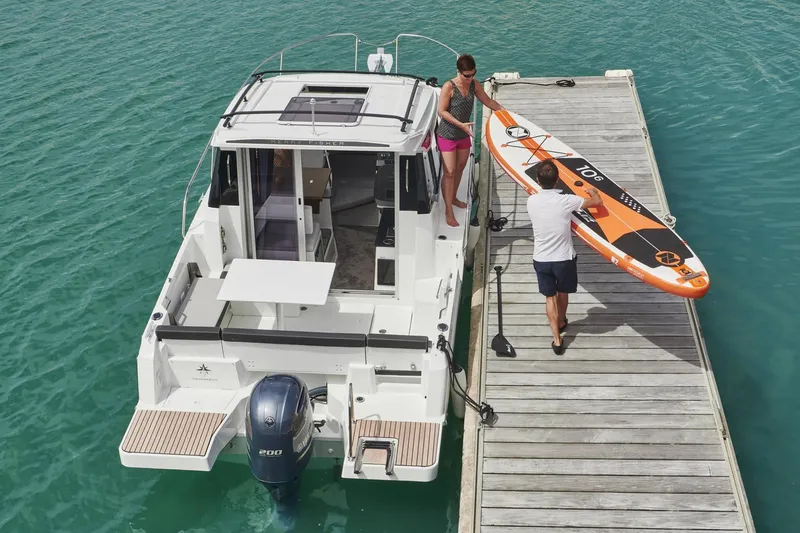 Slide: The Image of 2026 Jeanneau NC 795 Series 2 docked, with people handling a paddleboard on a sunny day. - 28