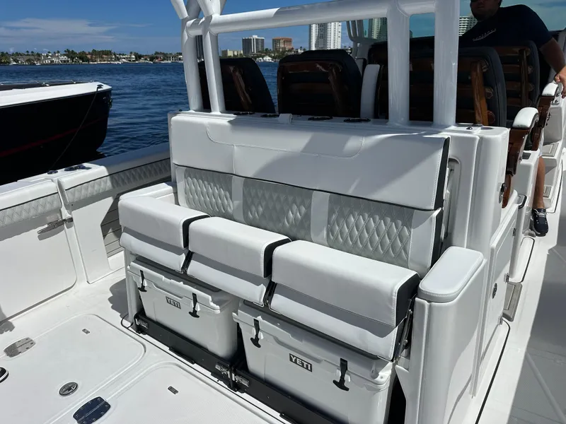 Slide: The Image of 2025 Blackfin 400 CC boat interior with cushioned seating and Yeti coolers on a sunny day. - 13