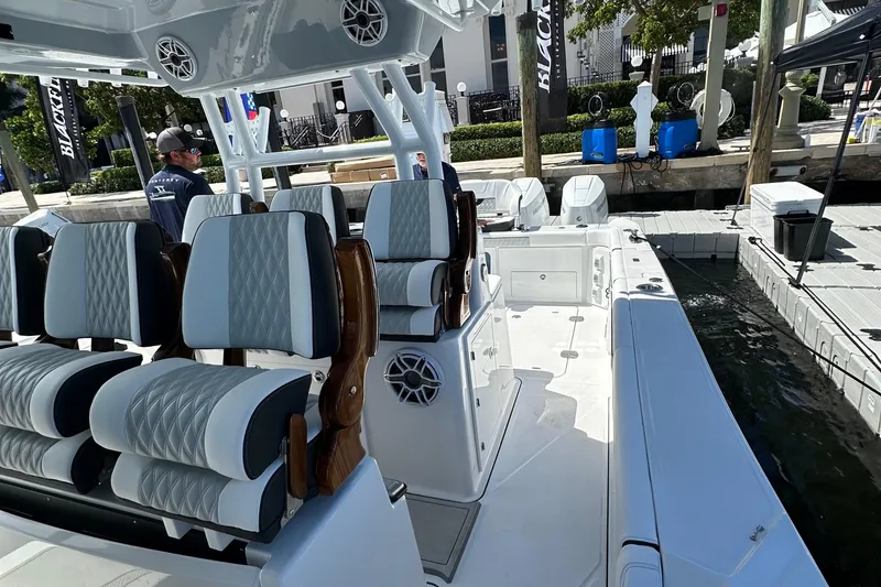 Slide: The Image of 2025 Blackfin 400 CC boat interior with luxurious seating at a marina dock. - 17