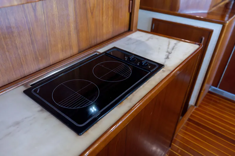 Slide: The Image of 1996 Jim Smith 60 Sportfish yacht kitchen with electric stovetop and wooden cabinetry. - 30
