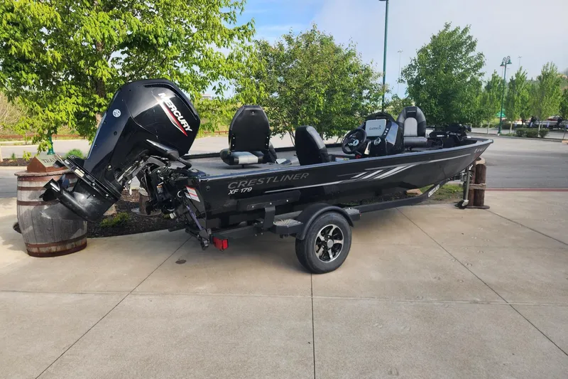 The Image of 2023 Crestliner XF 179 boat with Mercury engine on a trailer, parked outdoors. - 0