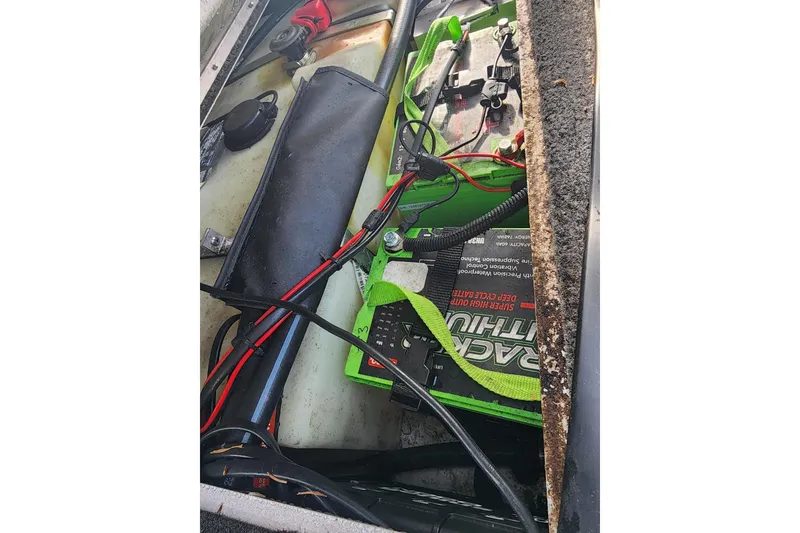 Slide: The Image of 2023 Crestliner XF 179 boat battery compartment with wiring and green battery. - 6