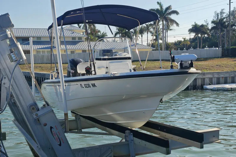 Slide: The Image of 2006 Boston Whaler 180 Dauntless boat on lift, with blue canopy, near waterfront homes. - 10