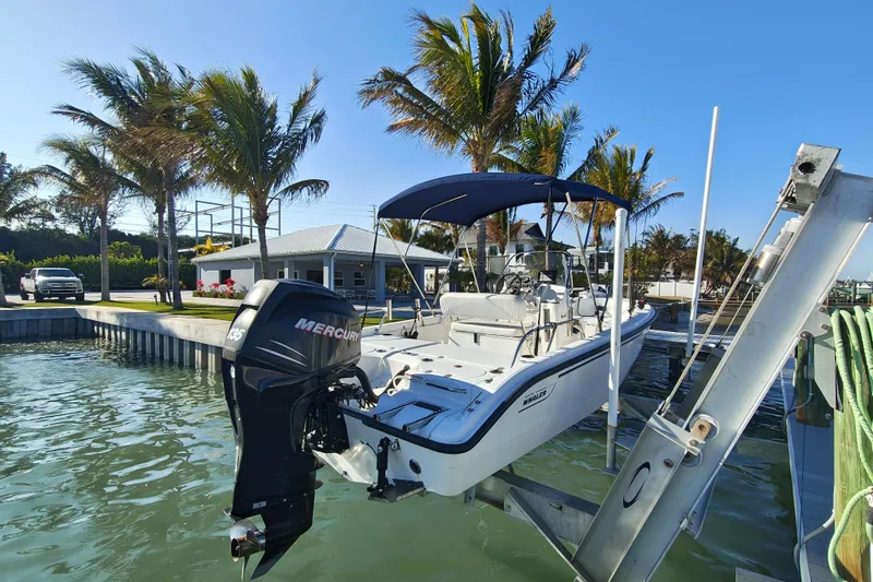 Slide: The Image of 2006 Boston Whaler 180 Dauntless boat docked, featuring a Mercury outboard motor and blue canopy. - 12