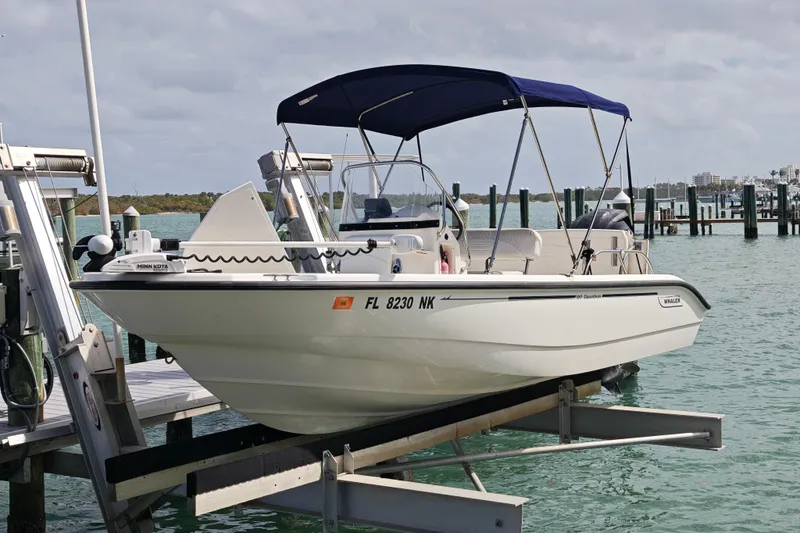 Slide: The Image of 2006 Boston Whaler 180 Dauntless boat docked with blue canopy on a lift. - 18