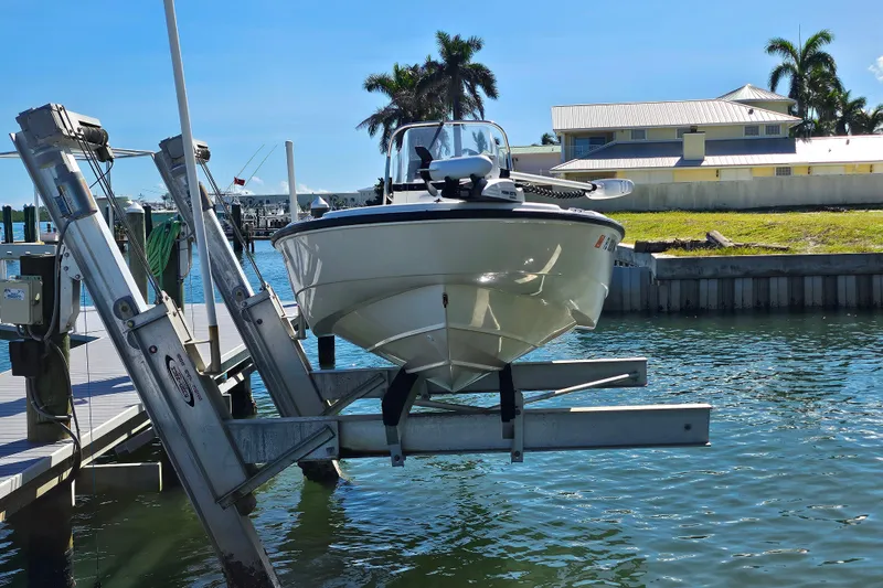 Slide: The Image of 2006 Boston Whaler 180 Dauntless boat on lift at marina, sunny day. - 2