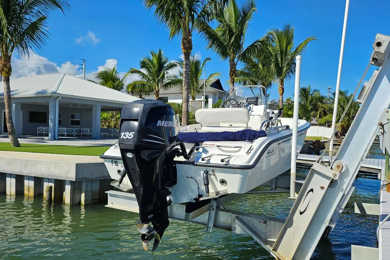 Slide: The Image of 2006 Boston Whaler 180 Dauntless boat on lift, surrounded by palm trees and waterfront home. - 6