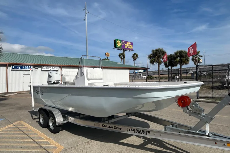 Slide: The Image of 2026 Coastal Skiff 212 boat on trailer, parked outdoors under clear sky. - 4