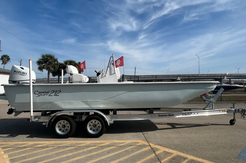 Slide: The Image of 2026 Coastal Skiff 212 boat on trailer, featuring Suzuki outboard motor, parked outdoors. - 5