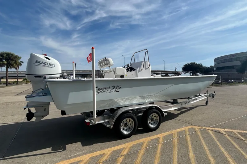Slide: The Image of 2026 Coastal Skiff 212 boat on trailer with Suzuki outboard motor, parked outdoors. - 6
