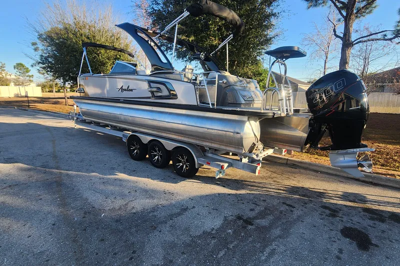 The Image of 2023 Avalon Excalibur 25' pontoon boat on trailer, parked outdoors. - 0