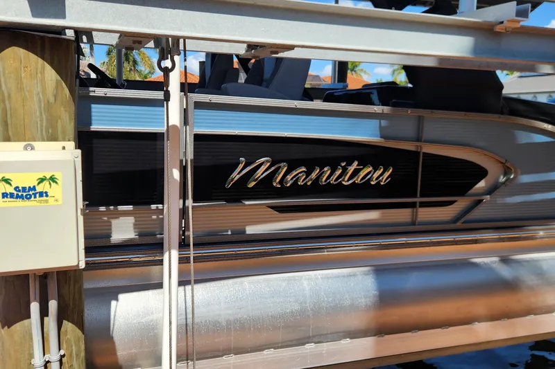 Slide: The Image of 2023 Avalon Excalibur 25' boat with "Manitou" branding, docked with GEM Remotes control box. - 28