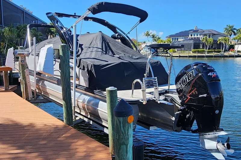 Slide: The Image of 2023 Avalon Excalibur 25' boat docked, covered, with powerful outboard motor. - 31