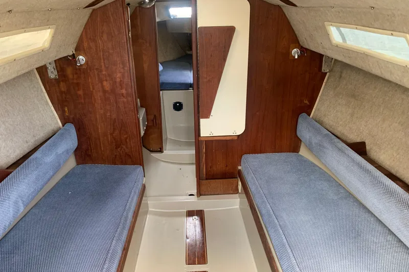 Slide: The Image of Interior of a 1985 Oday 272 sailboat with blue cushioned seating and wooden accents. - 13