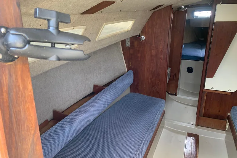 Slide: The Image of Interior of a 1985 Oday 272 sailboat, featuring wooden paneling and blue seating. - 14