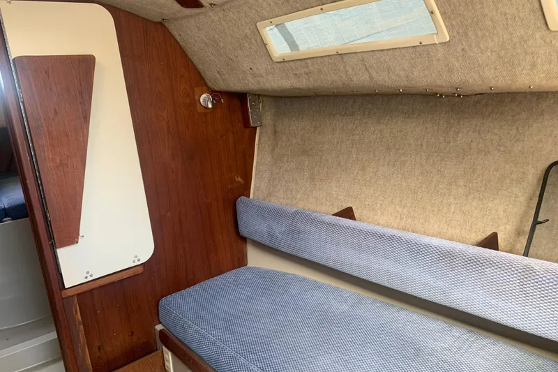 Slide: The Image of Interior of a 1985 Oday 272 sailboat with wooden paneling and blue cushioned seating. - 19