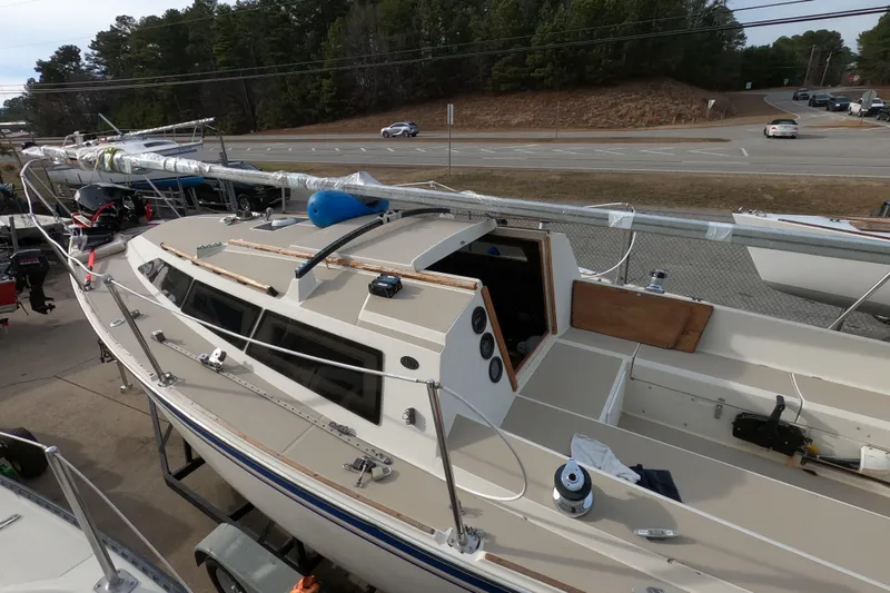 Slide: The Image of 1985 Oday 272 sailboat on trailer, parked near a road with trees in the background. - 6