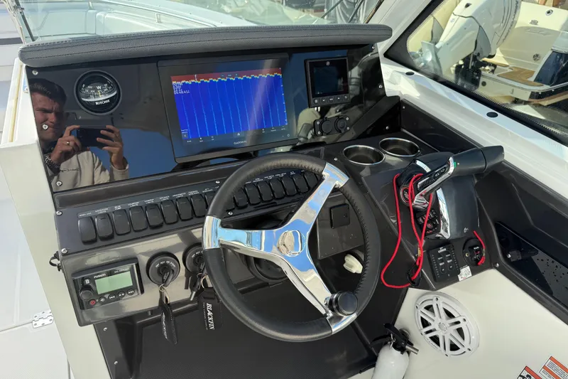 Slide: The Image of 2022 Blackfin 272 DC boat dashboard with steering wheel, navigation system, and controls. - 15