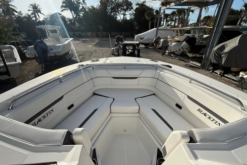 Slide: The Image of 2022 Blackfin 272 DC boat interior with white seating, docked outdoors. - 17