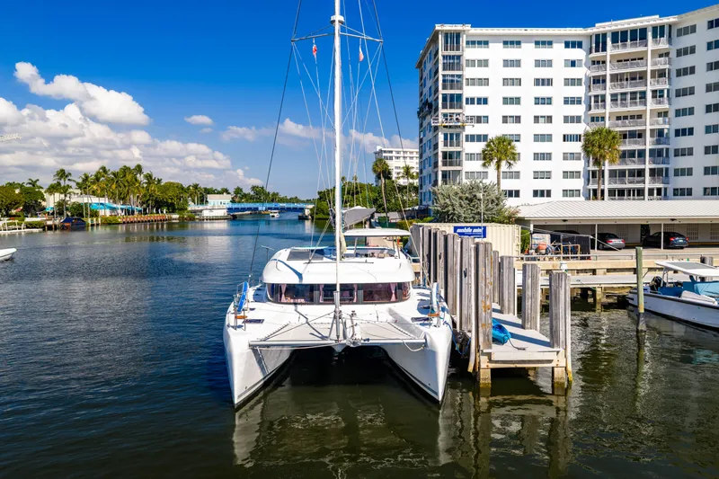 Slide: The Image of 2018 Lagoon 42 catamaran docked near modern buildings. - 2