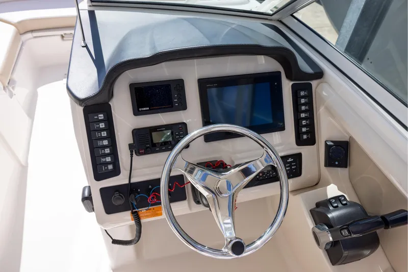 Slide: The Image of 2018 Robalo R247 Dual Console boat dashboard with steering wheel and electronic controls. - 10