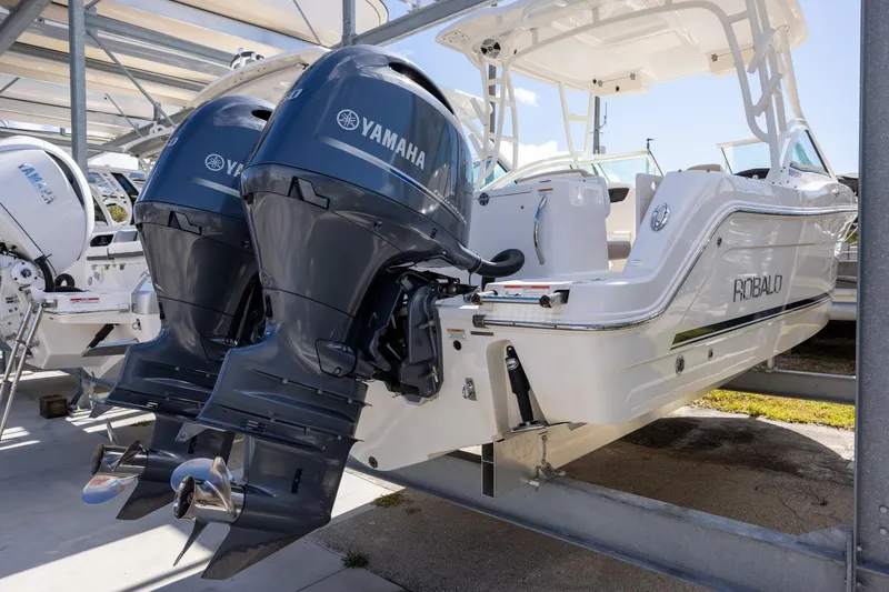 Slide: The Image of 2018 Robalo R247 Dual Console with twin Yamaha outboard engines, docked in a marina. - 4