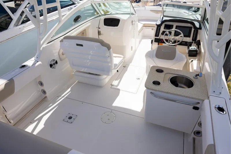 Slide: The Image of 2018 Robalo R247 Dual Console boat interior with seating, steering, and sink. - 7