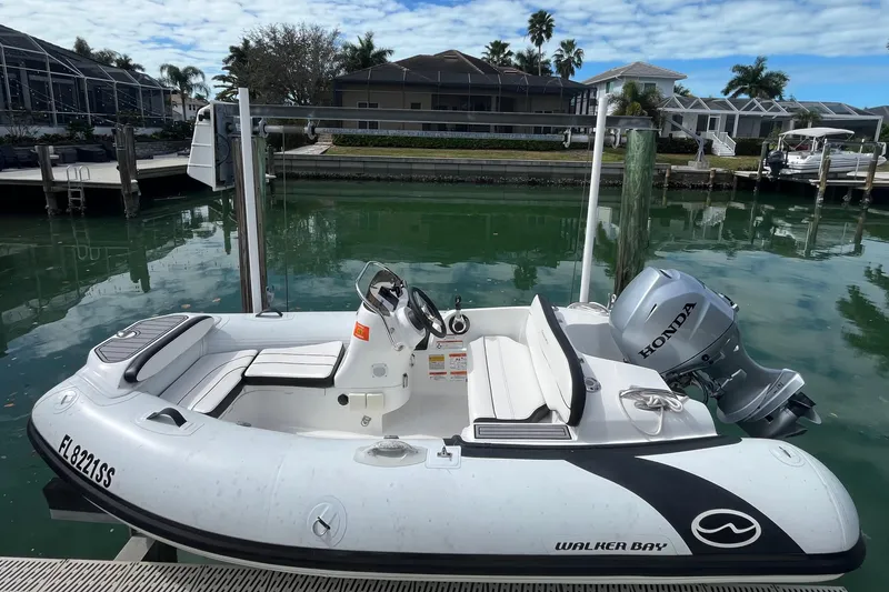 Slide: The Image of 2020 Walker Bay Generation 360 boat with Honda motor docked by waterfront homes. - 1
