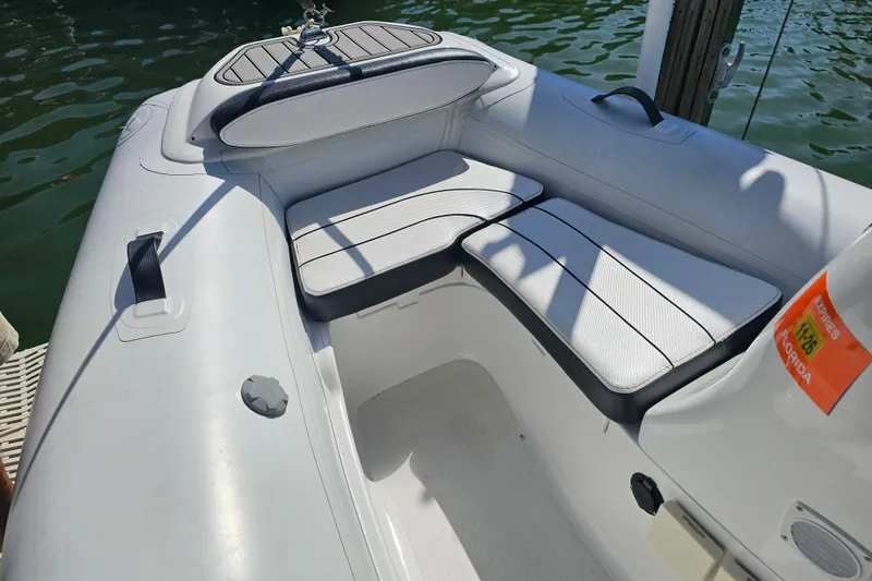 Slide: The Image of 2020 Walker Bay Generation 360 boat interior with cushioned seating, docked on calm water. - 13