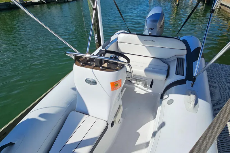 Slide: The Image of 2020 Walker Bay Generation 360 boat interior with seating and controls, docked on calm water. - 18